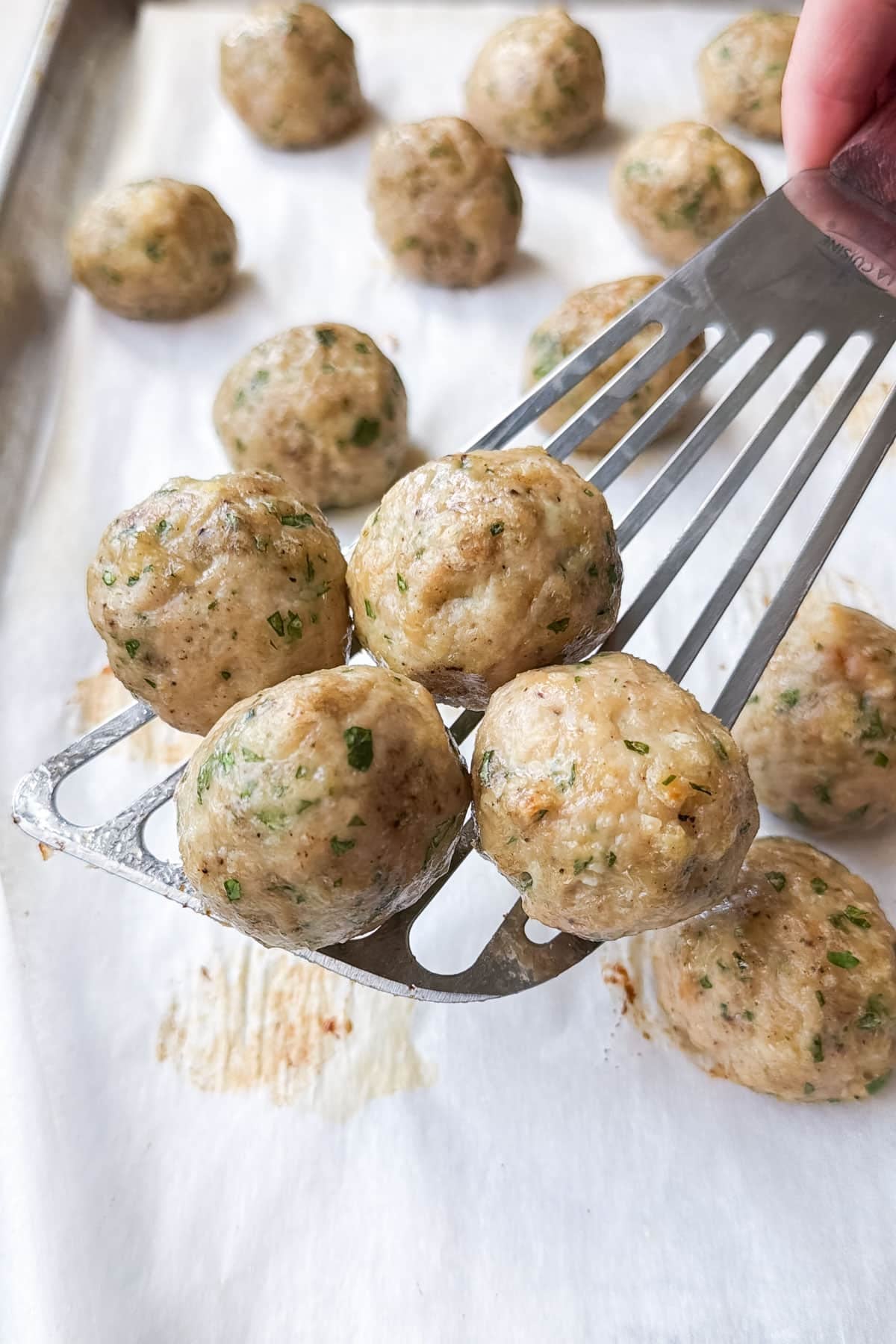 Golden baked chicken meatballs on a spatula, ready for the butter chicken sauce