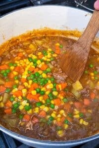 Frozen carrots, corn, and peas are stirred into a pot of shepherd's pie soup.