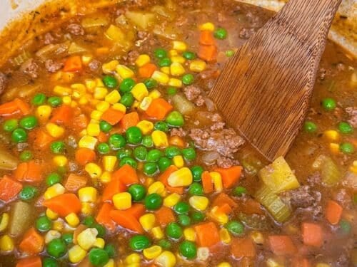Frozen carrots, corn, and peas are stirred into a pot of shepherd's pie soup.