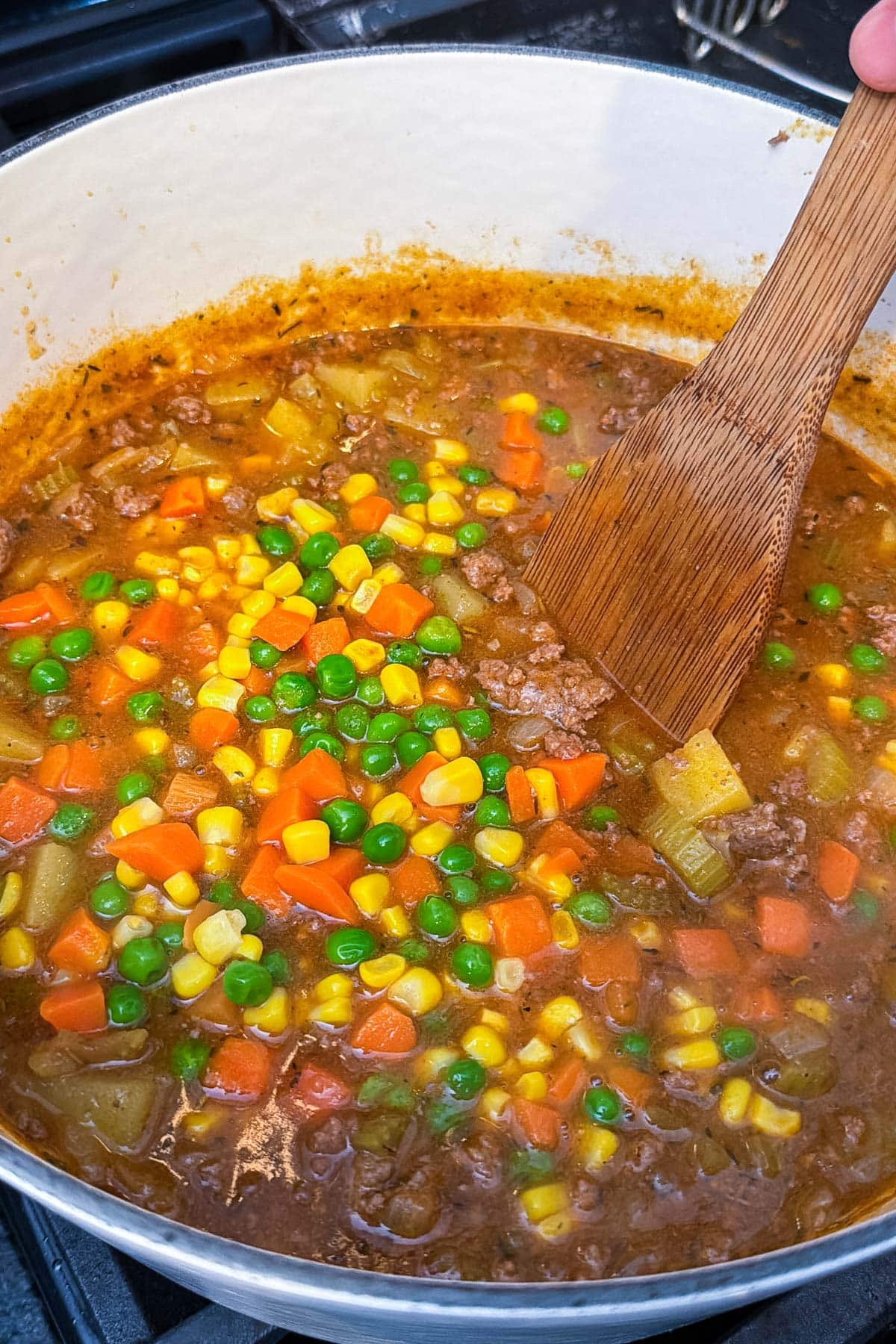 Frozen carrots, corn, and peas are stirred into a pot of shepherd's pie soup.